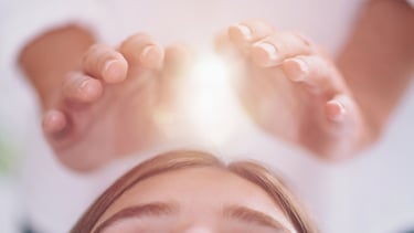 Hands projecting light hovering above a head