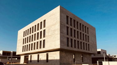 Wide architectural shot of a modern minimalist concrete office building in Casablanca, sharp geometric lines, bright Moroccan afternoon sunlight, deep blue sky, 35mm architectural photography