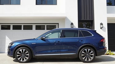 A premium modern vehicle parked in front of a clean, contemporary Memphis residence, bright daylight, 35mm lens, sharp focus