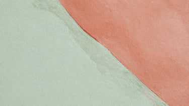 Extreme close-up of a mural detail, showing delicate watercolor layers of diluted terracotta and sage green on a textured eggshell wall, soft natural light