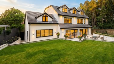 Modern luxury home with a white exterior, large lawn, and warm evening lighting.