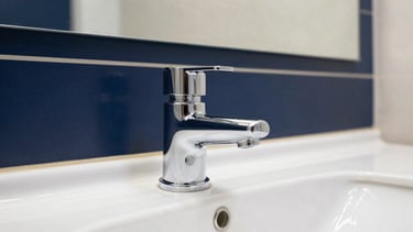 Close-up of a pristine, polished chrome fixture in a high-end corporate restroom, reflecting clean architectural lines and soft lighting, bright natural daylight, sharp focus, 35mm