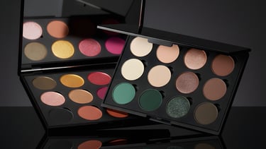 Professional eyeshadow palettes with matte and shimmer pigments on a reflective surface.
