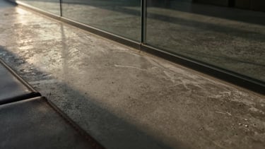Extreme close-up texture shot of a polished concrete surface meeting a sleek glass panel, with a hint of dark leather in the foreground, dramatic low-key lighting, high contrast, editorial style.
