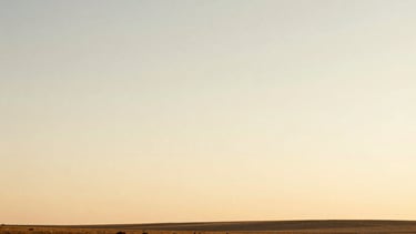 Wide panoramic natural landscape at golden hour, soft cream and earth tones, expansive sky, low horizon, warm editorial photography
