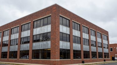 Wide environmental shot of a professional brick office building exterior in Keasbey, NJ, overcast daylight, desaturated steel tones, realistic textures, 35mm lens