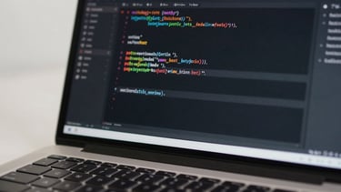 Close-up of an Android Studio code editor on a laptop screen, readable Kotlin syntax visible, bright neutral studio light from the left, keyboard edge in frame