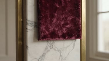 Close-up of elegant interior design material samples, rich plum velvet, white marble with dark grey veining, brushed brass accents, soft warm natural light