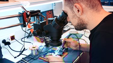 a man in a black shirt is looking at a microscope