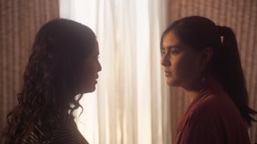 Dos mujeres de pie una frente a la otra en una habitación.