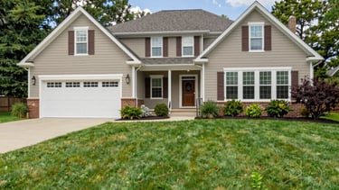 A team trimming bushes and sweeping the front porch of a cozy home on a sunny day.