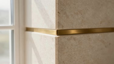 Extreme close-up of a mitered corner transition between two slabs of soft cream travertine stone, brushed brass fixture visible, sharp focus, architectural detail