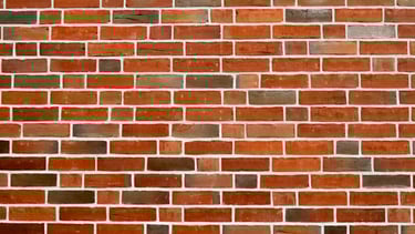 Nahaufnahme einer gleichmäßigen Wand aus roten und braunen Klinkersteinen 