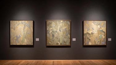 Wide panoramic view of a gallery wall in warm directional light, three large oil paintings hung at measured intervals, textured impasto surfaces catching the museum spotlight, deep charcoal wall receding into shadow on both sides