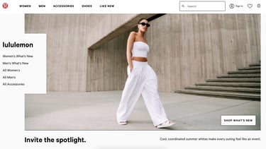 A woman wears a white tube top, white wide pants, and white sandals against a concrete wall.