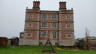 Soulton Hall in Shropshire with a pyramidal sculpture in front of it