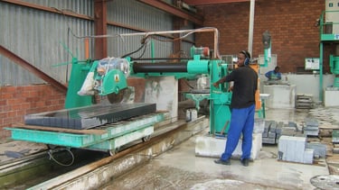 A saw operator busy cutting a granite slab into kerbs at the Teggs Granite factory