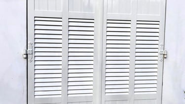 Volets battants blancs à persiennes.