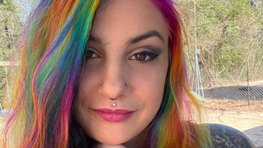 Beautiful woman that is tattoo artist with colorful hair and piercings on her chest