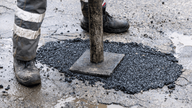 Stamping down asphalt pothole repair on roadway