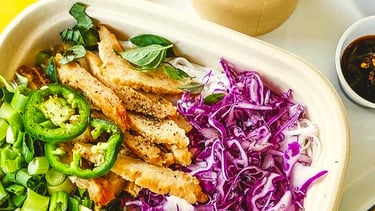 A savory plant-based patty adds a bold twist to traditional pho, nestled among rice noodles,
