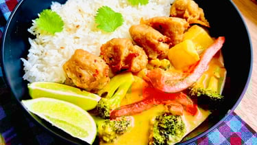 A vibrant red curry sauce envelopes crispy popcorn chicken, blending bold Thai spices with herb