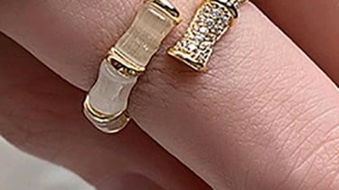 a woman's hand holding a gold ring with a diamond