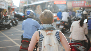 a woman walking down a busy street in a busy city