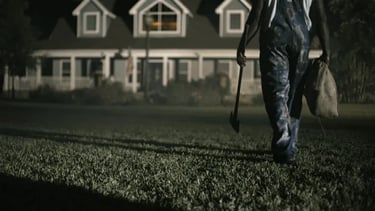 a man in overalls walking in the grass