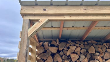 a chord of chopped wood logs stacked on top of each other in a wooden storage shed