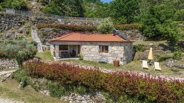 a small stone house with a red roof and a red roof