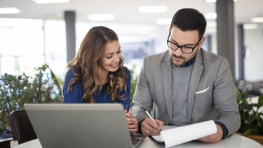 Profesionales revisando documentación y trabajando juntos frente a un ordenador en un entorno de ofi