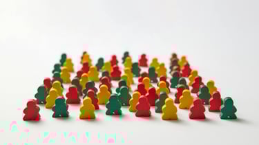 Houten poppetjes in rood, groen en geel door elkaar, symboliseert schoolpraktijk en samenwerking.