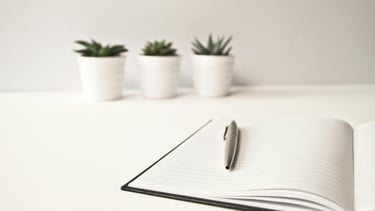 Notitieboekje met pen, klaar voor persoonlijke reflectie en het vastleggen van één vraag per overleg