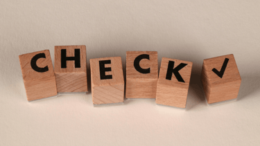 Blokjes met letters C-H-E-C-K en een vinkje als symbool voor korte reflectie en checkmoment.