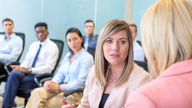 a woman in a pink jacket is talking to a man in a suit