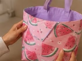 Bolso tipo tote hecho a mano con estampado de sandía rosa, forro morado y asas.