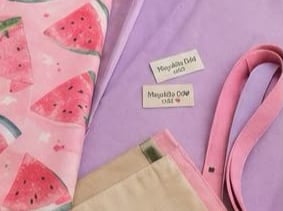 ela hecha a mano con estampado de sandía rosa y artículos de costura, junto con etiquetas de ropa.