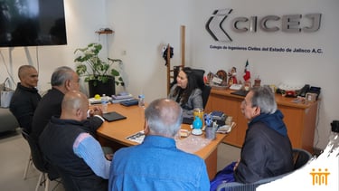 Professional meeting at CICEJ office with civil engineers discussing projects around a wooden desk.