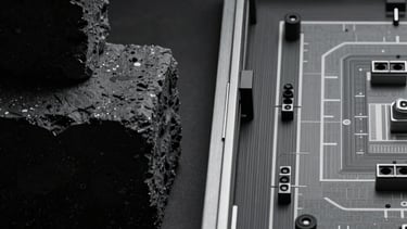 A photograph showing the contrast between a rough geometric blockout and a finished game level side-by-side. Analytical and intellectual presentation. Midnight black and silver gray.