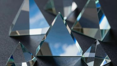 Abstract photography of light reflecting through glass prisms, casting sky blue and slate blue light across a dark surface, symbolizing innovation and clarity.