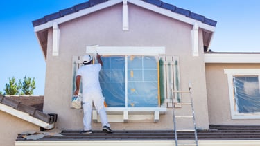 Worker painting the outside of a house.