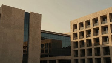 Wide environmental shot of modern Dubai architectural lines, minimalist concrete and glass, warm golden hour light, rich desaturated tones, 35mm