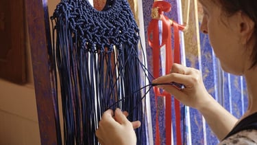 Mujer artesana entrelazando hilo de macramé para hacer un colgante