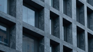 Clean, sharp detail of a modern architectural facade with repeating geometric patterns. Dark blue grey and slate tones, North American / International style.