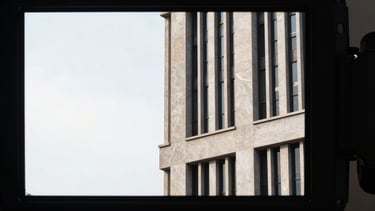 Stark urban architectural details seen through a camera monitor, high-contrast lighting, minimalist composition with expansive negative space on the left