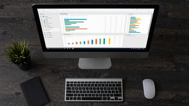An overhead organized desk layout featuring a clean, dark-themed data analysis dashboard on a desktop monitor showing structured metrics