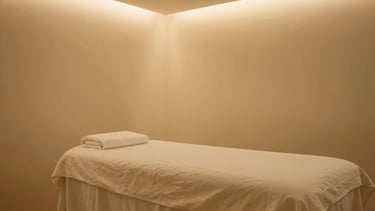 Wide environmental shot of a serene, empty luxury spa treatment room, soft ambient golden lighting, minimalist design, elegant details