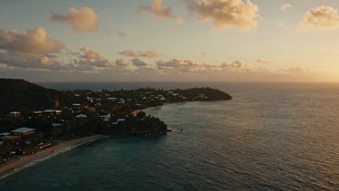 Cinematic wide shot of a dramatic Caribbean coastline at golden hour, deep depth of field, captured with a professional drone.