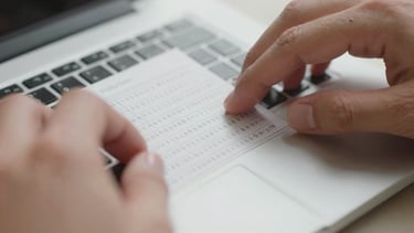 Extreme close-up of hands typing a long alphanumeric tracking number into a clean white input field on a laptop keyboard, neutral studio lighting, clinical and sharp, no warm tones, fingers mid-keystroke visible